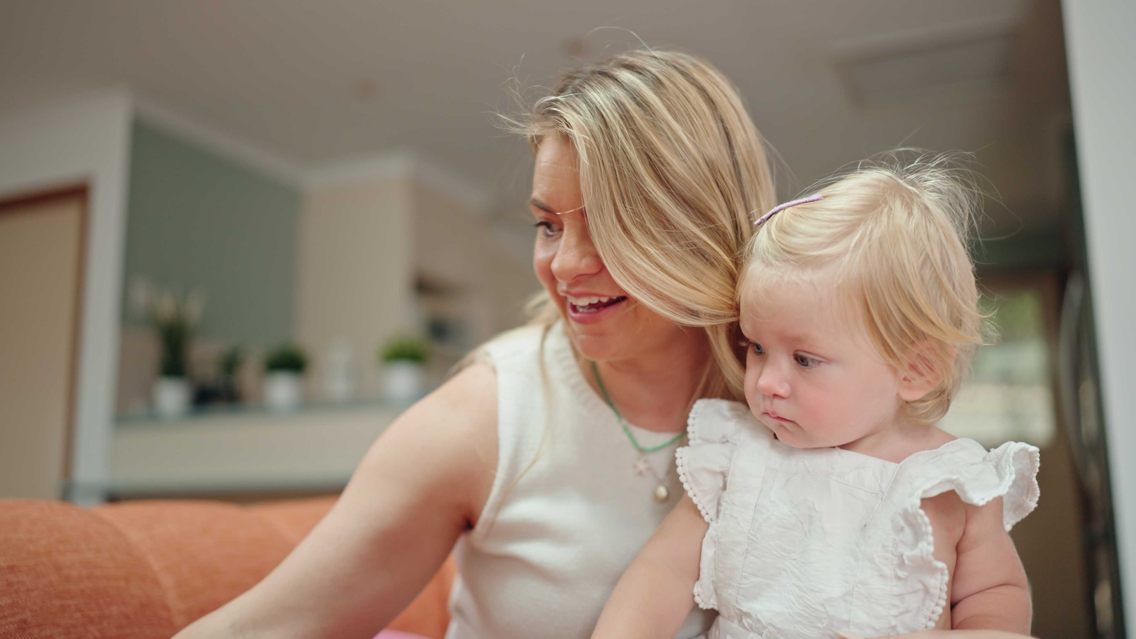 Adult holding a smiling toddler in a comfortable open-plan living room