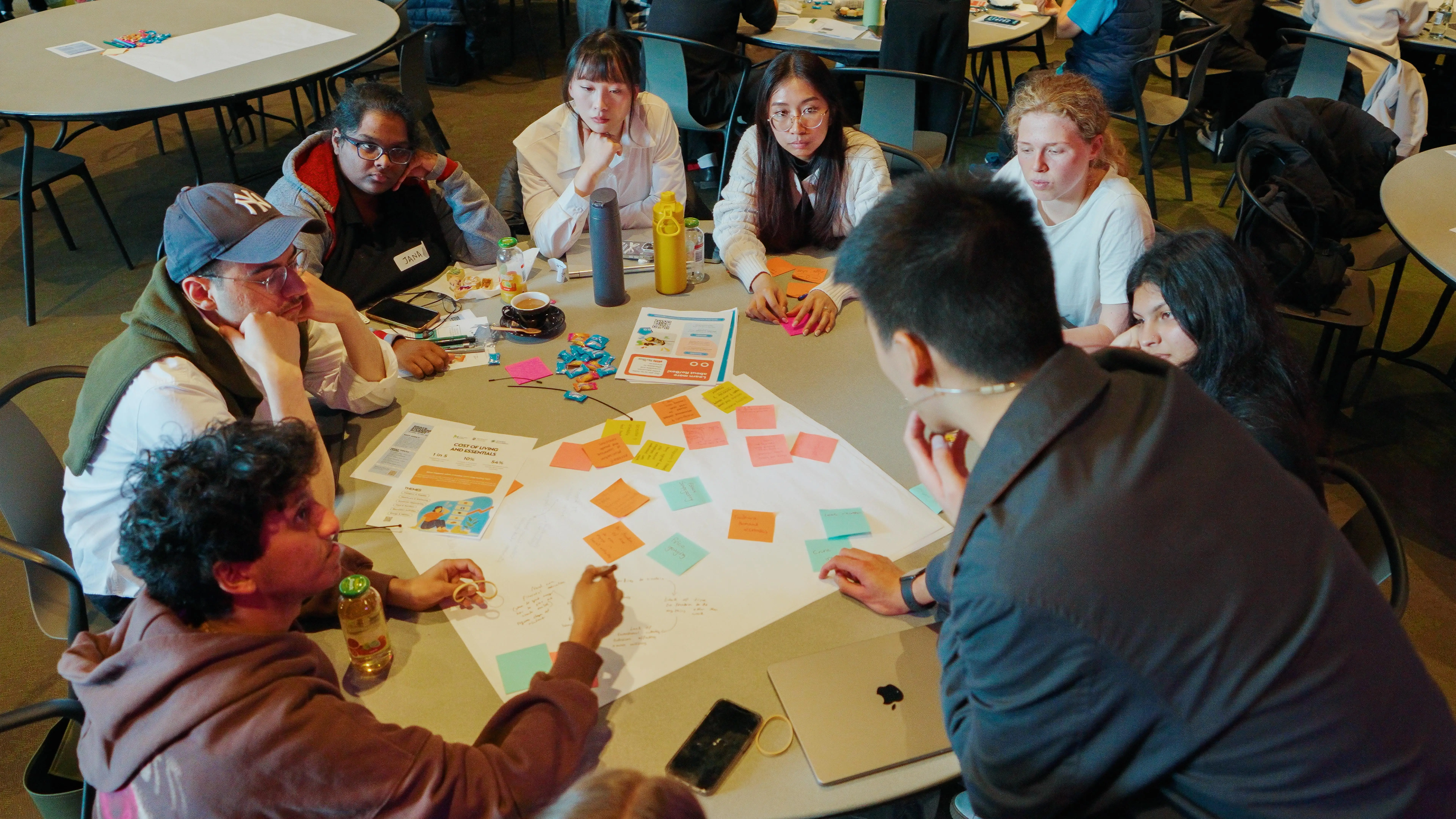 Group of diverse people collaborating around a table covered with sticky notes and papers.