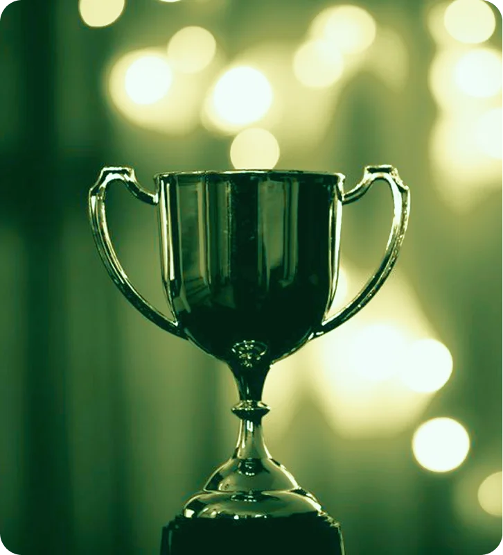 Shiny trophy cup with two handles against a blurred background of lights.