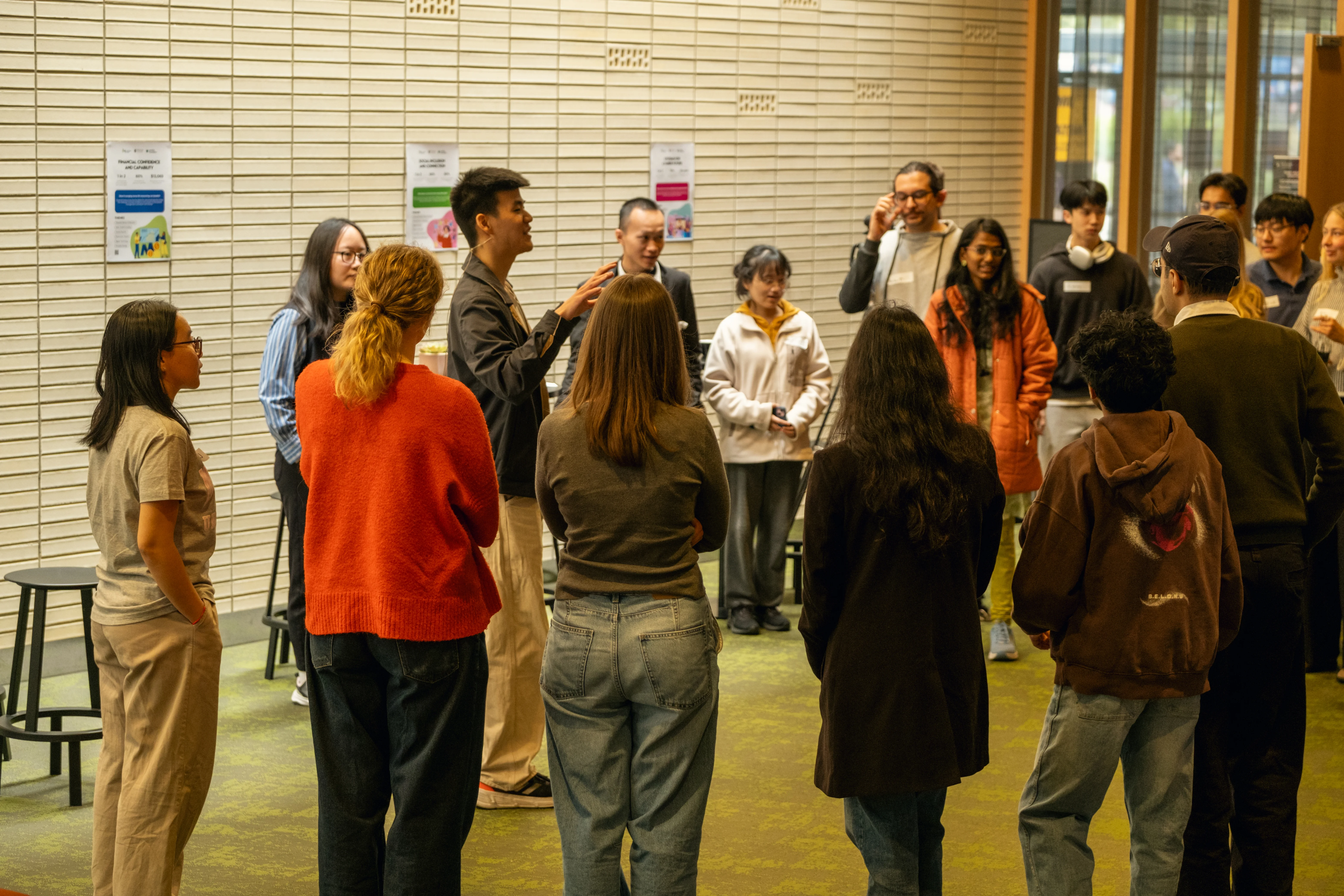 Group of people standing in a circle indoors, engaging in discussion or activity.