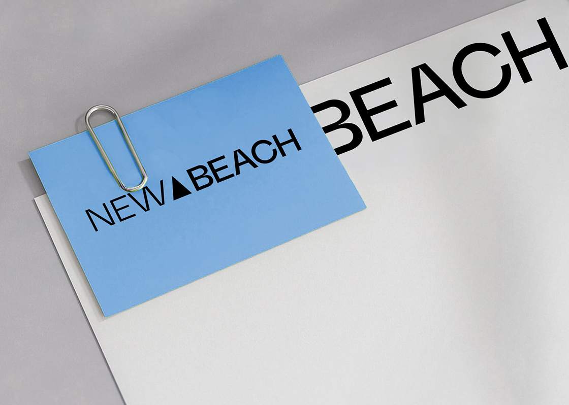 A blue New Beach business card held by a paperclip to a white sheet printed with large black type