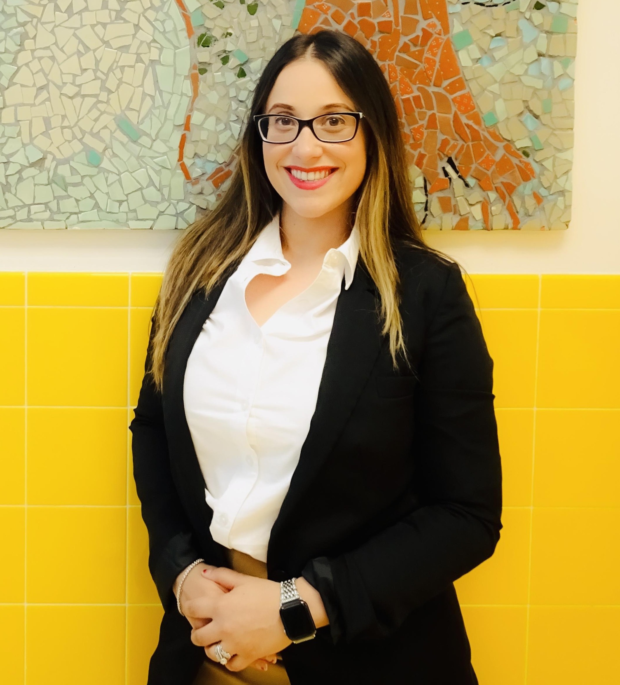 Aliza Hernandez-Velez staff portrait in front of colorful mosaic mural