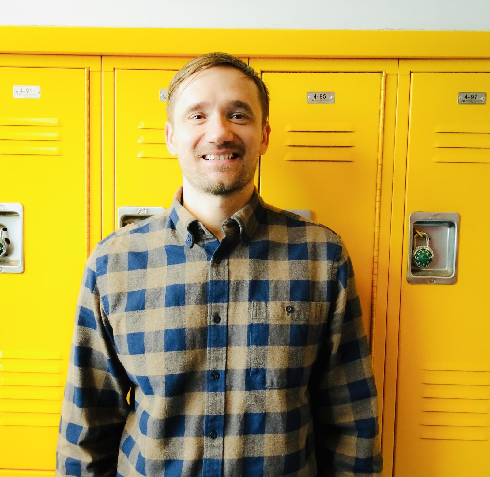 David Weber staff member posing by yellow hallway lockers