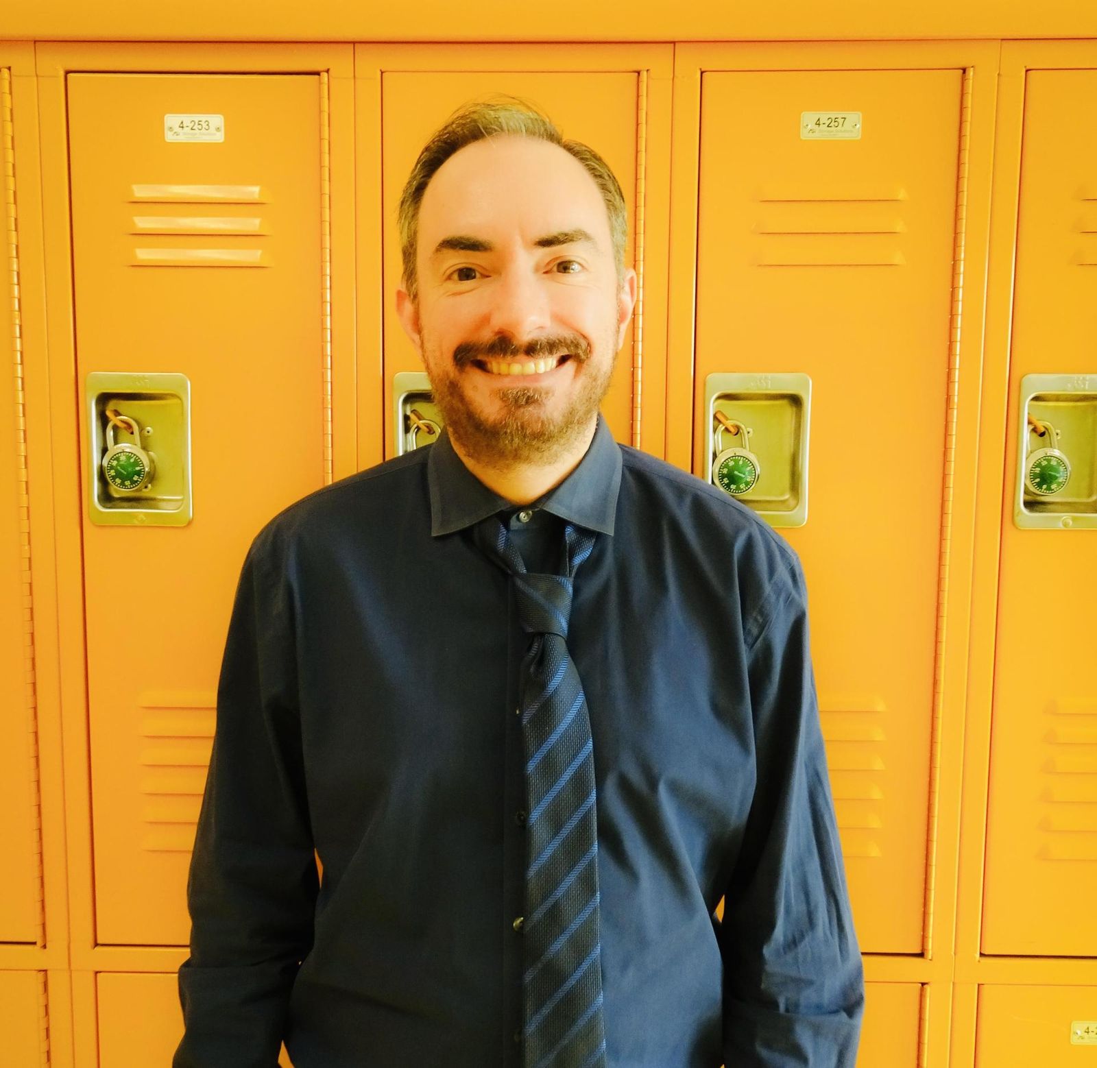 Michael Rosenthal smiling in front of yellow school lockers