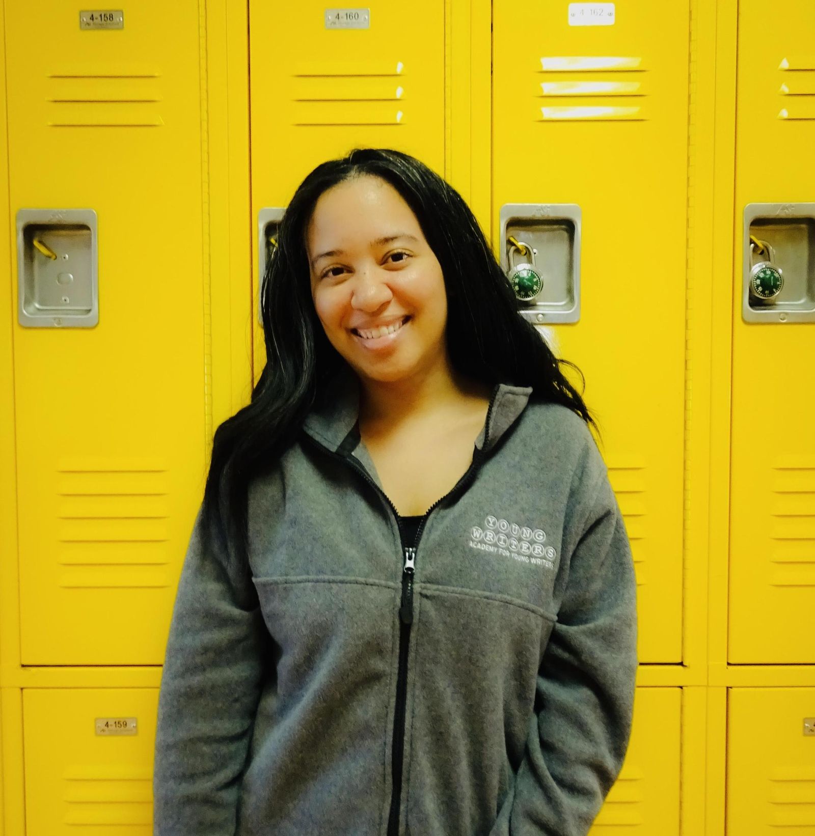 Michelle Andrews wearing a Young Writers Academy hoodie by school lockers
