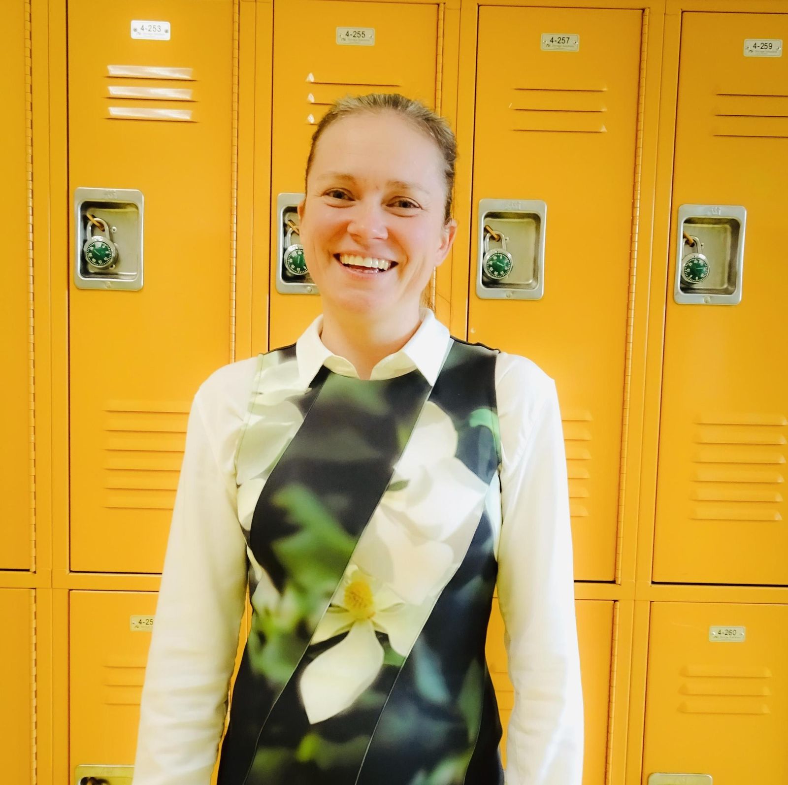 Smiling staff member Rabi Whitaker standing in front of school lockers