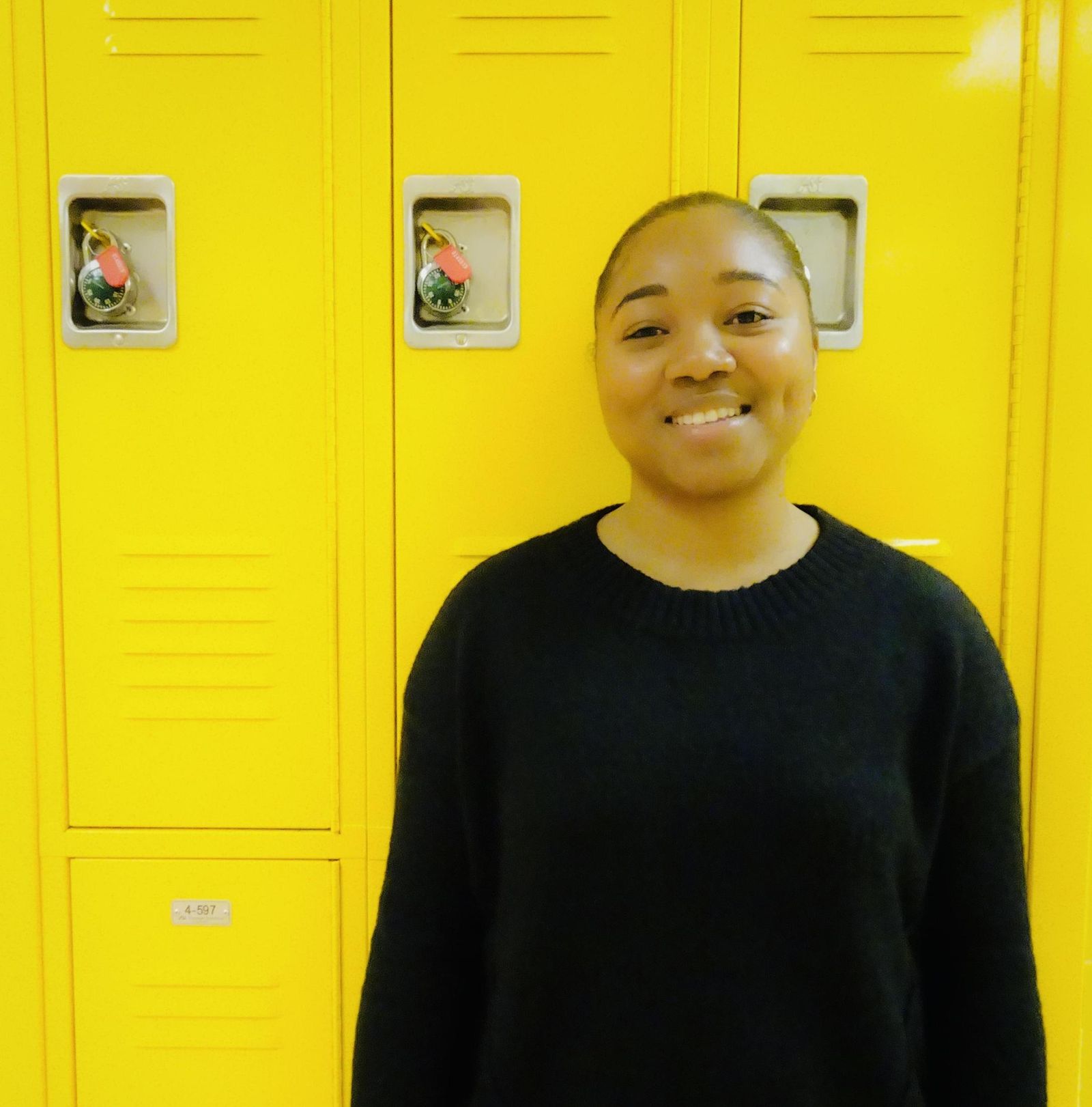 Shamarie Williams smiling in front of yellow school lockers