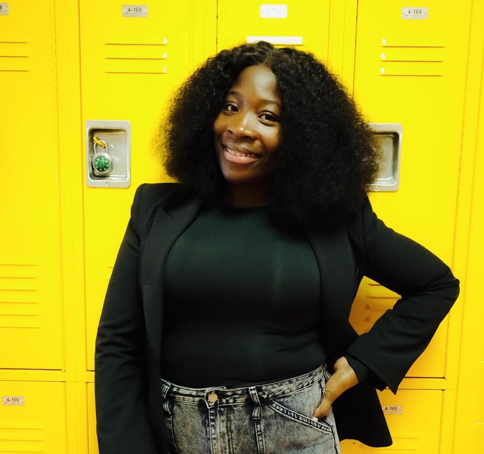 Trishawna Mattis posing confidently by bright yellow school lockers