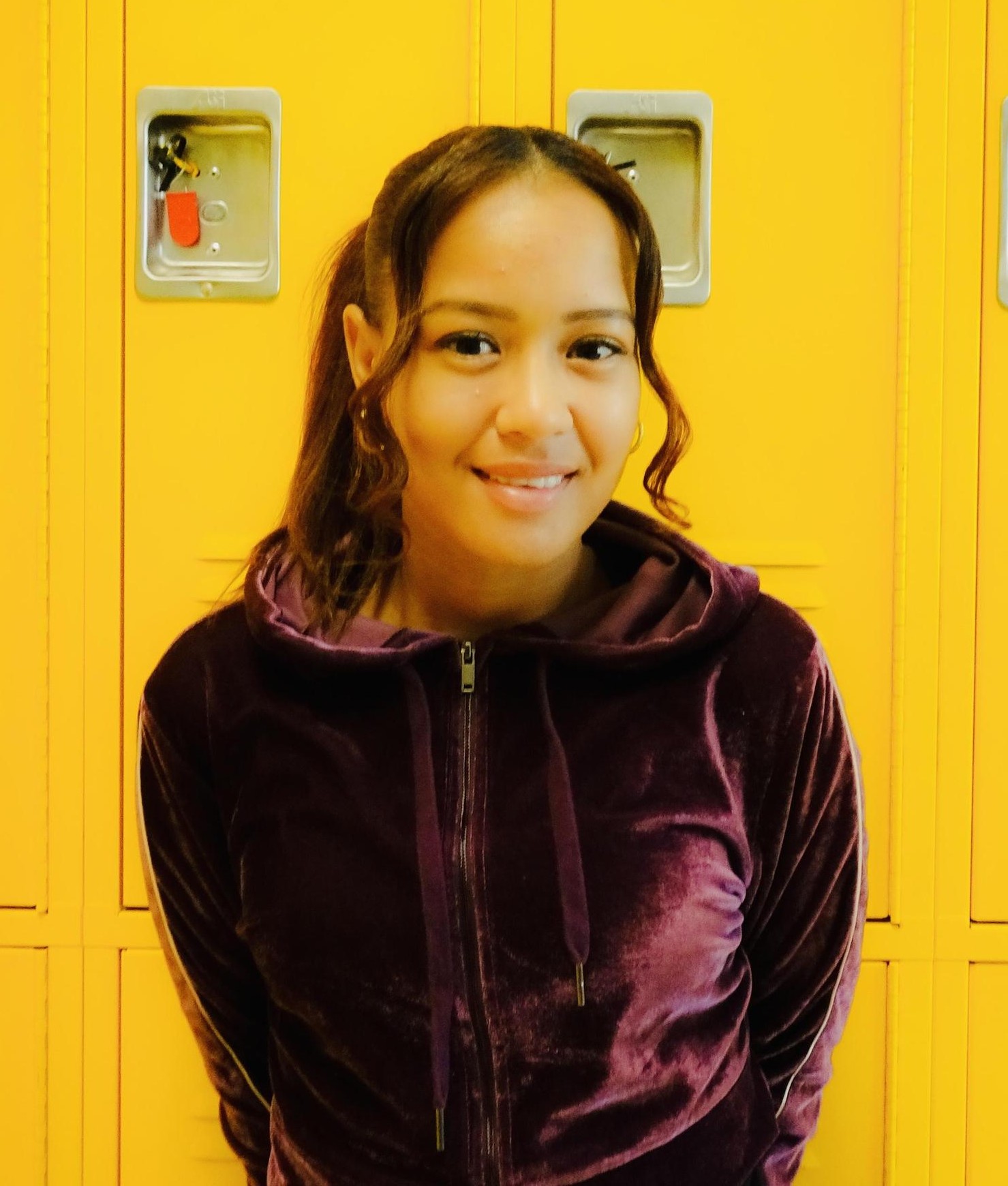 Anabel Bautista posed by bright yellow hallway lockers