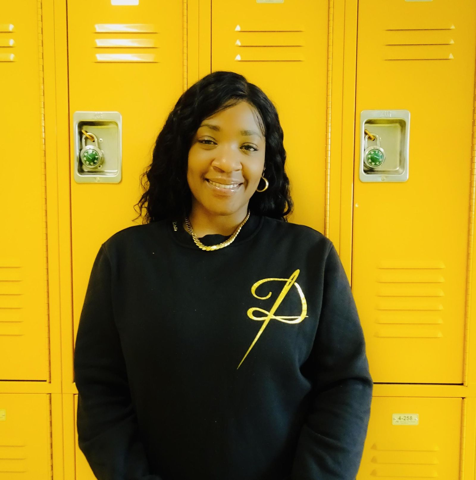 Candice Hinds staff portrait beside yellow hallway lockers
