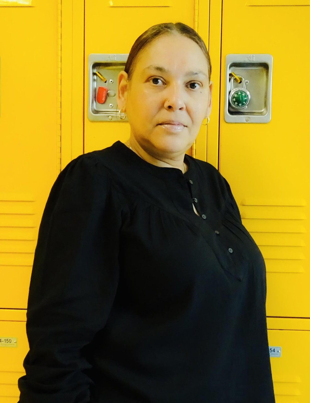 Staff member Iliana Hernandez posing in front of yellow school lockers