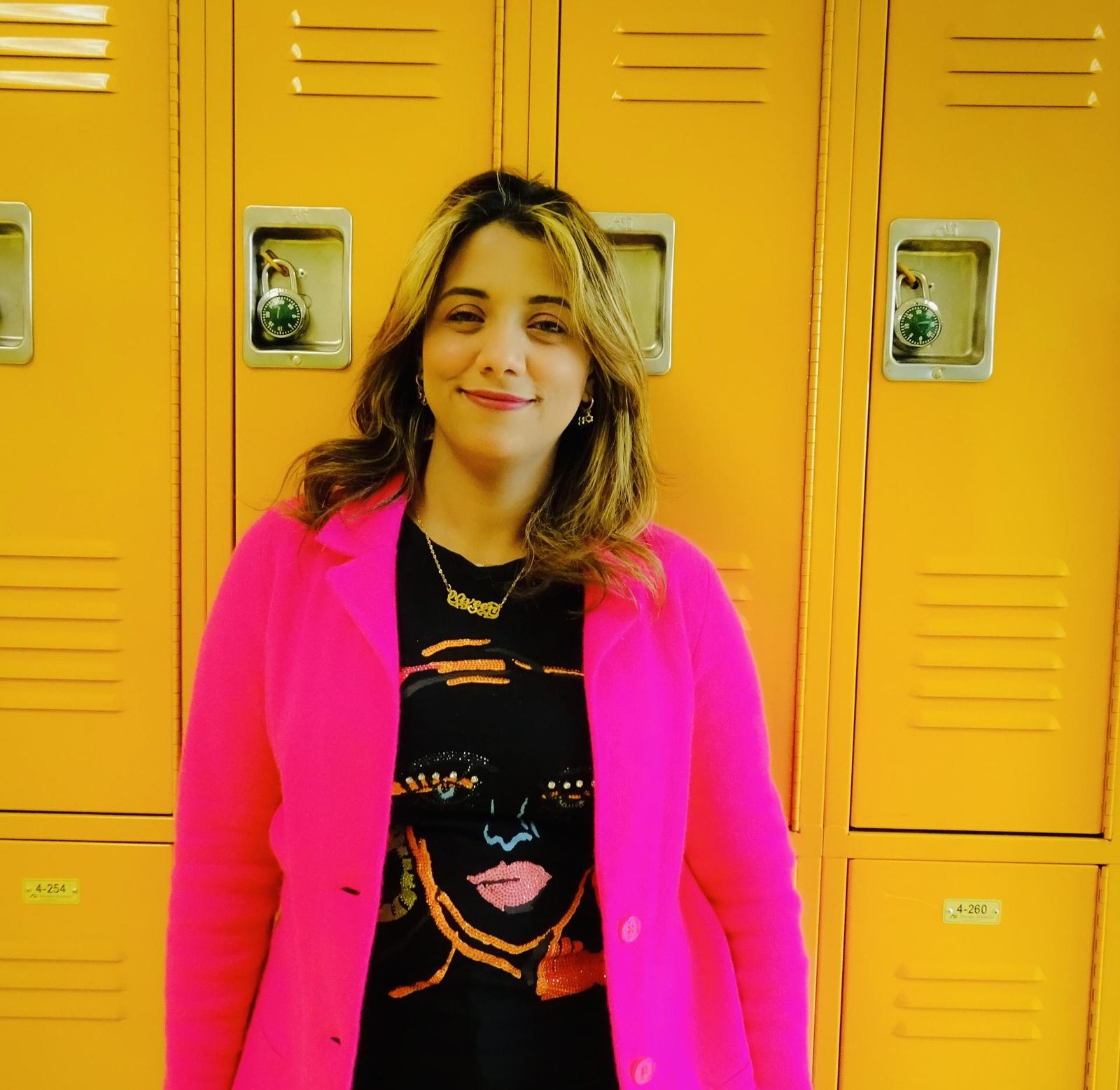 Staff member Niveen Ahmed smiling in front of yellow school lockers