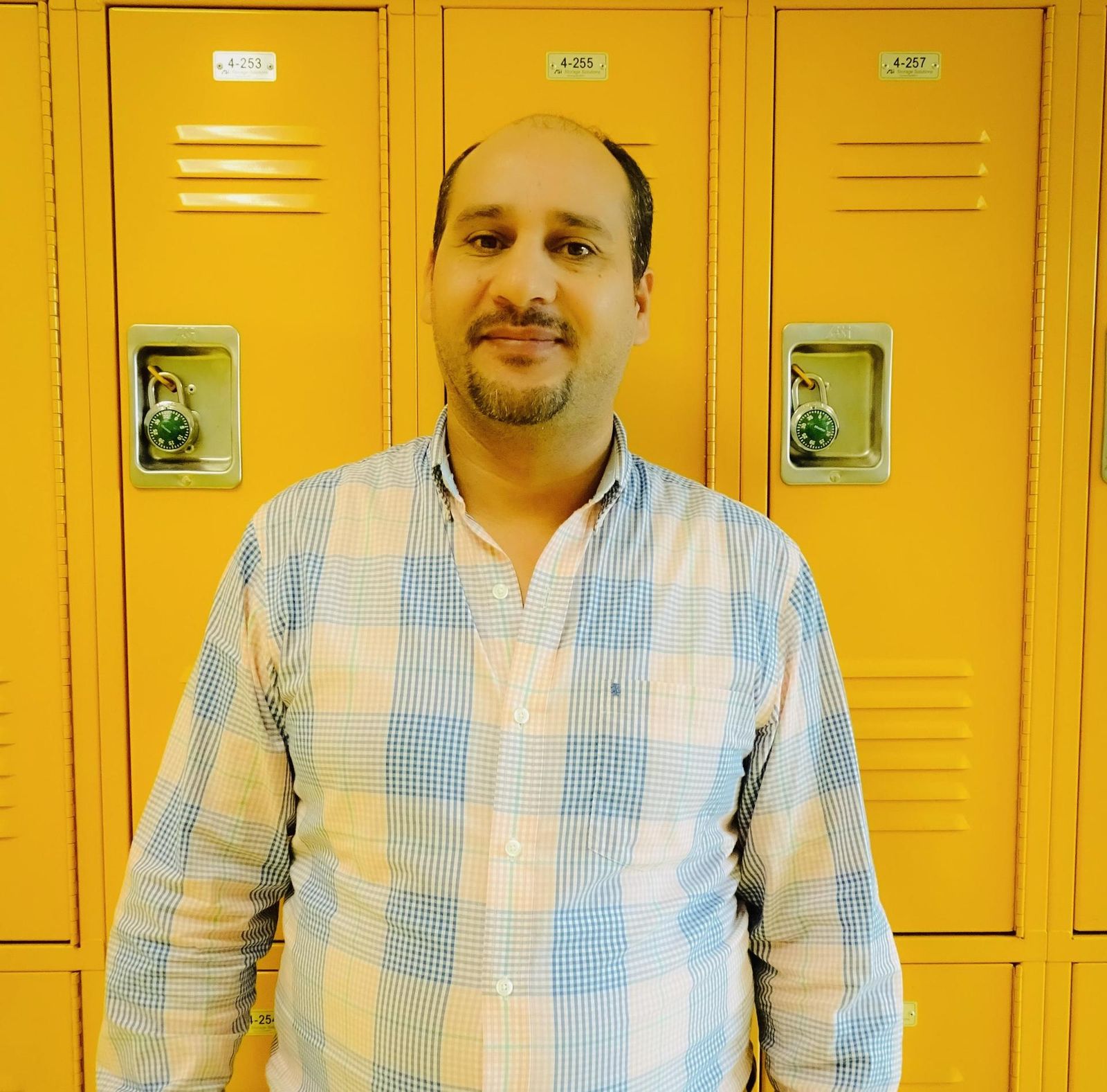 Staff member Nabil Saleb standing in front of school lockers