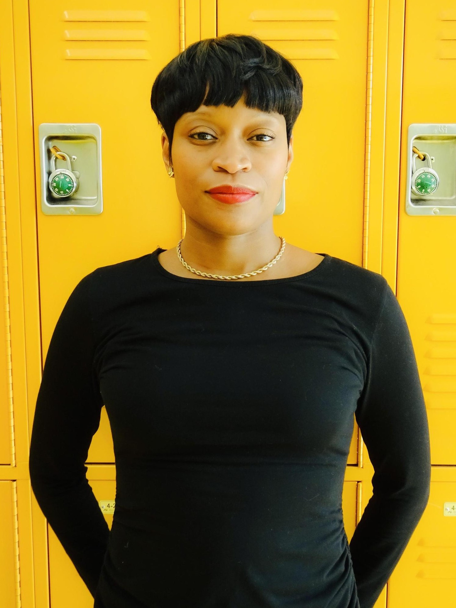 Tara Mann staff member standing in front of yellow school lockers