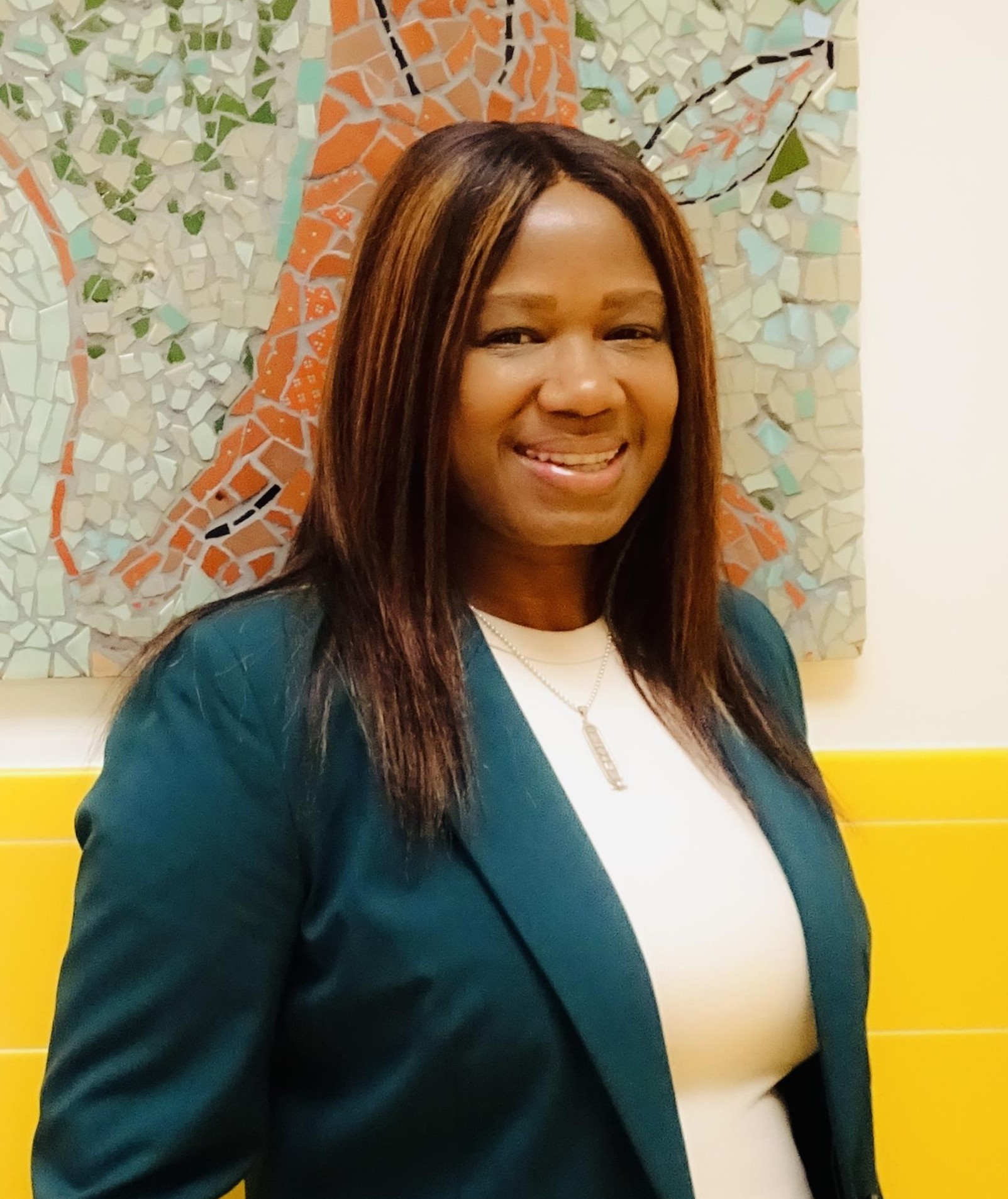 Tanisha Brown smiling in front of a colorful mosaic artwork
