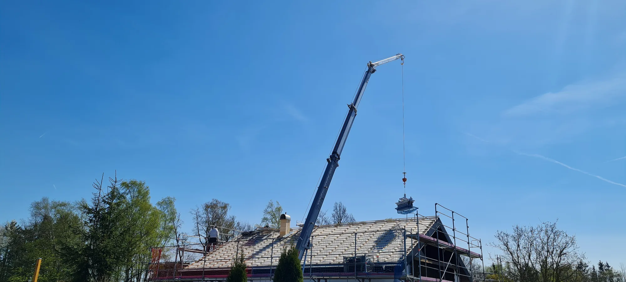 Autokran hebt Dachmaterial auf die Baustelle eines Einfamilienhauses