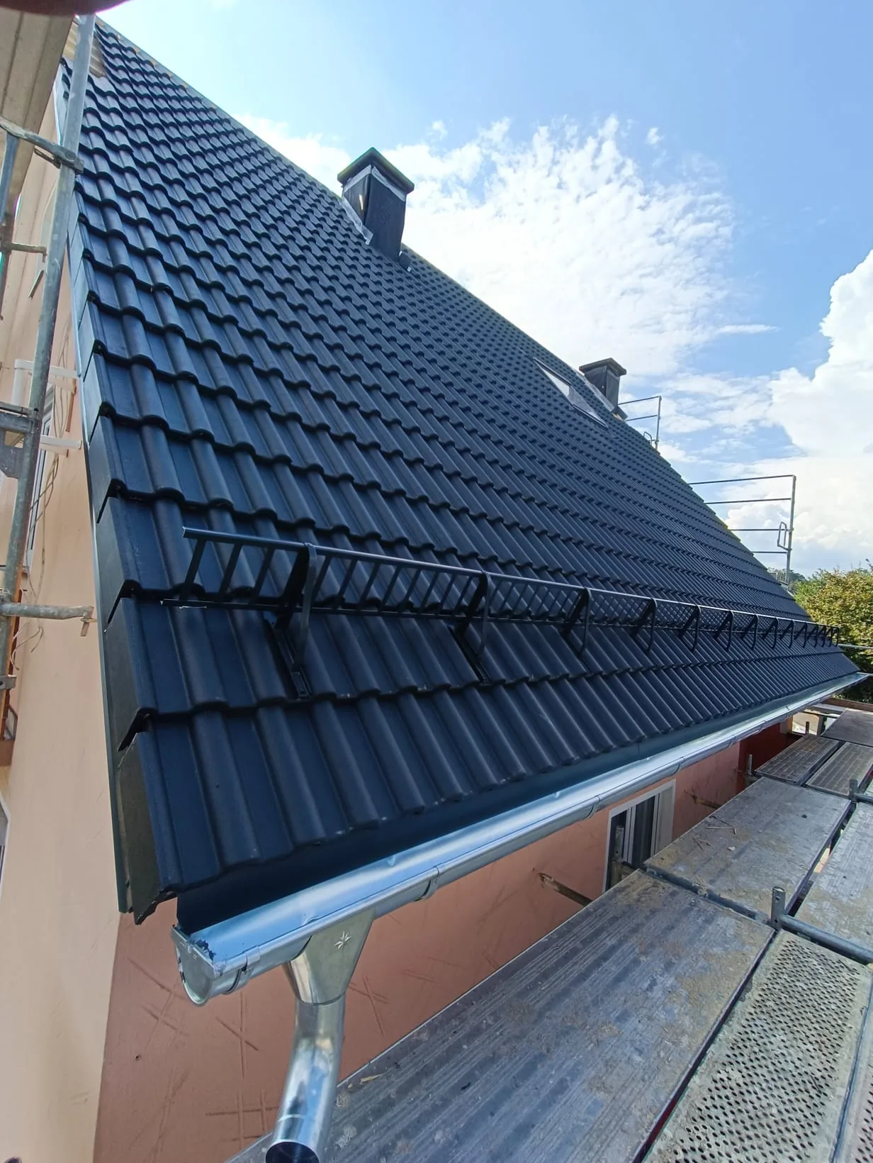 Neu eingedecktes Ziegeldach mit Schneefanggitter und neuer Zink-Dachrinne