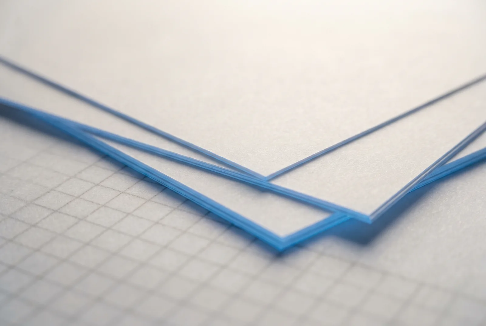 Sheets of white and blue card layered at an angle on gridded paper, New Beach journal