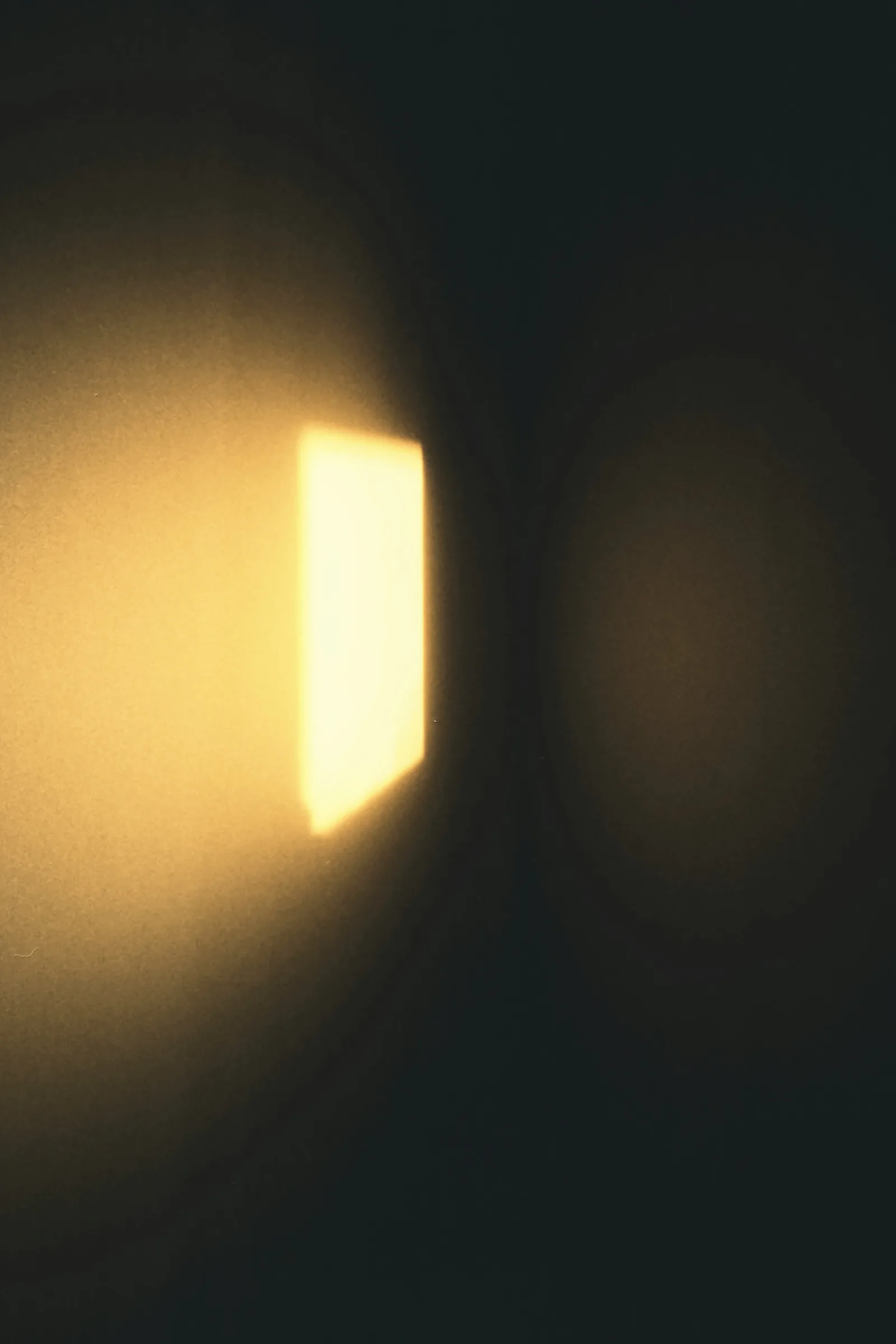 A soft rectangle of warm light falling on a dark wall, New Beach journal