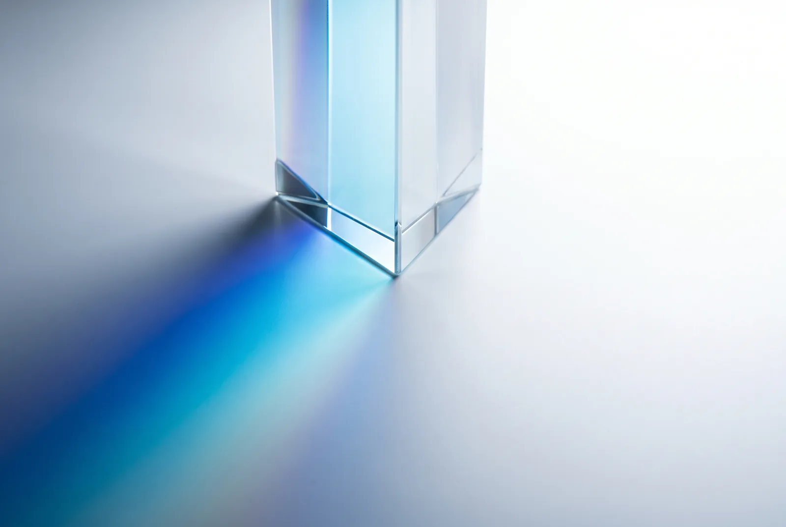 A glass block on a white surface throwing a streak of blue refracted light, New Beach journal