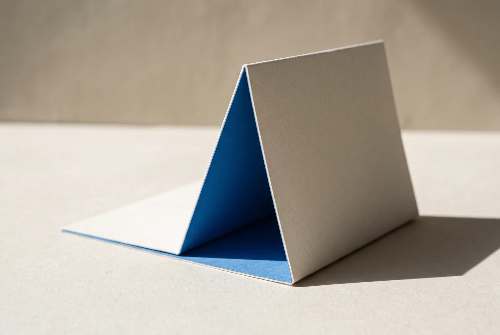 A sheet of card folded and standing like a tent, its inner face bright blue, New Beach journal