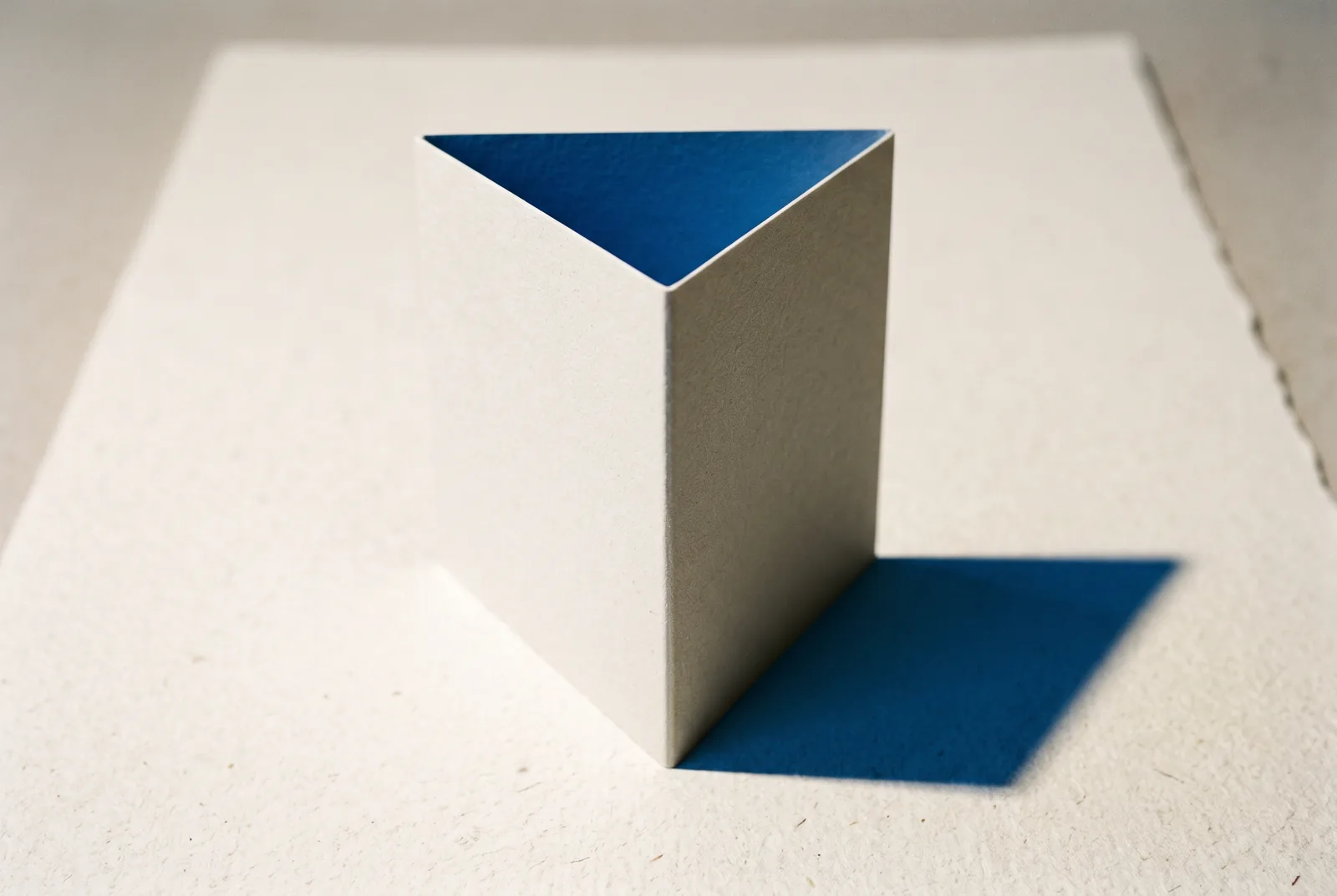 A sheet of cream card folded into a standing triangular form, its inner faces bright blue, New Beach journal