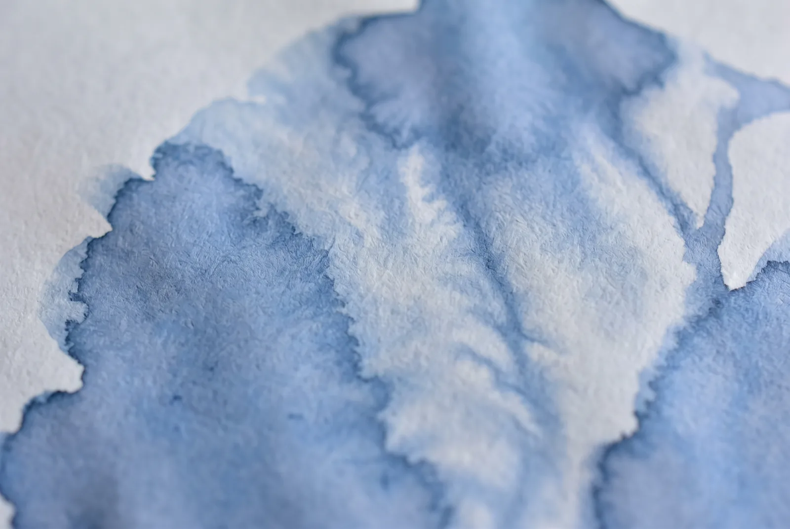 A blue watercolour wash bleeding into heavily textured paper, New Beach journal