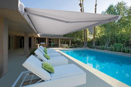 White retractable awning extended over a poolside patio with outdoor lounge seating