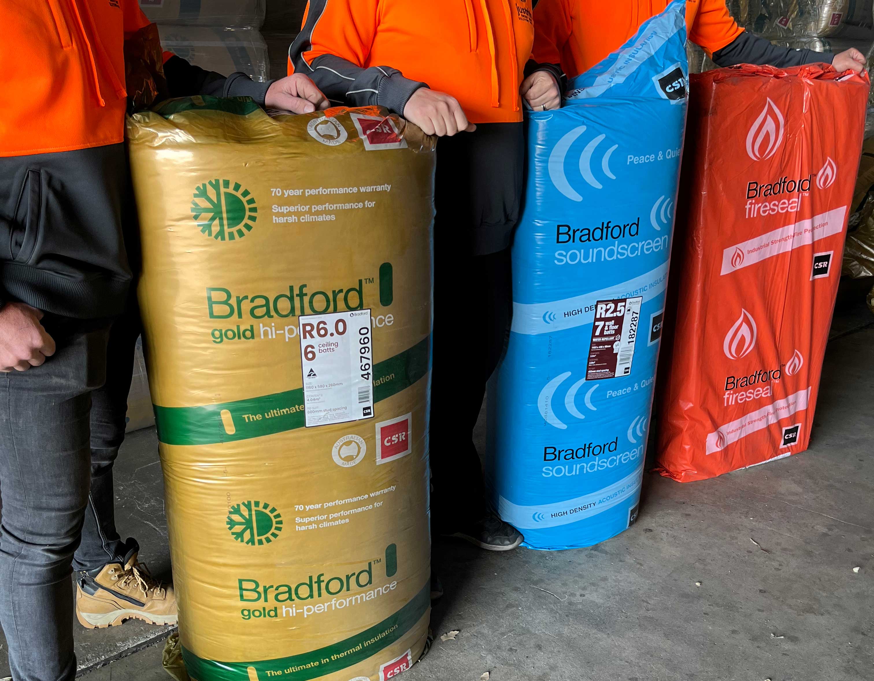 Two workers holding packs of Earthwool and Bradford insulation batts