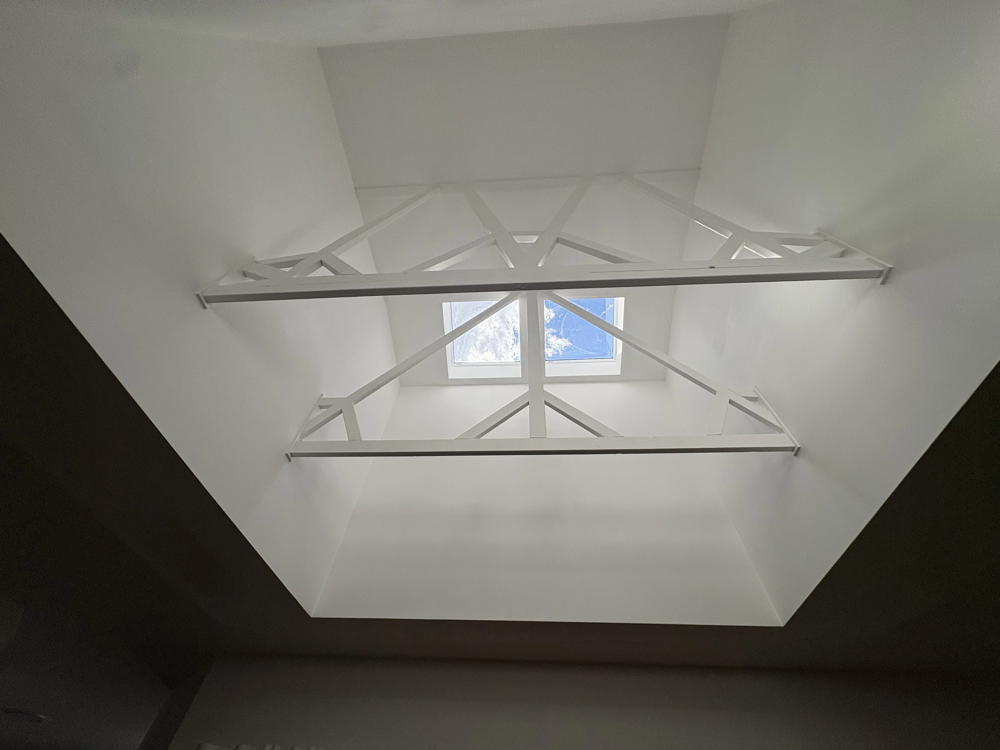 Skylight at the top of a tall white plastered shaft in a raked dining room ceiling