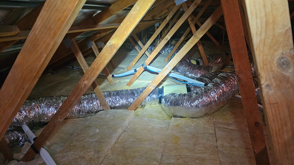 Ceiling insulation batts laid over existing insulation between timber roof trusses in a roof cavity