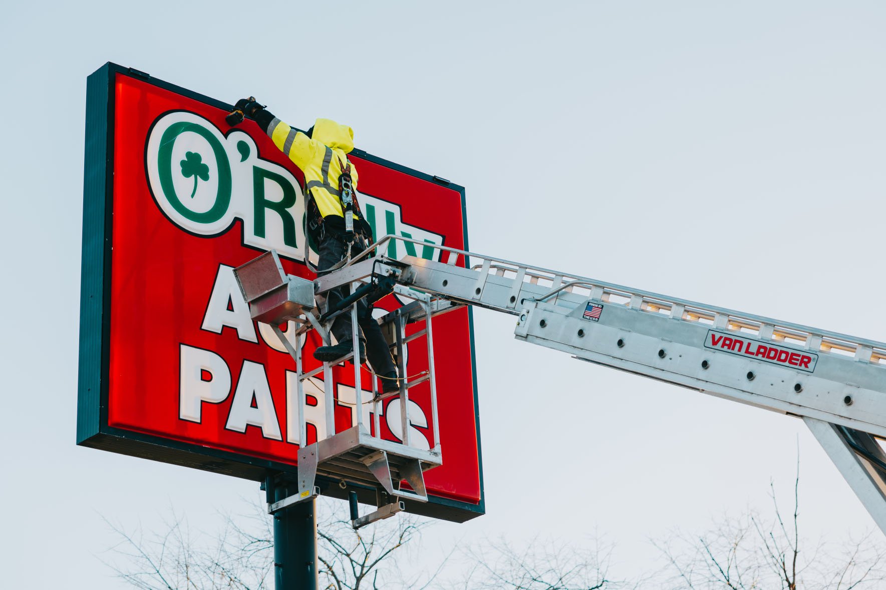 Rick Signs Van Ladder bucket truck servicing the illuminated O’Reilly Auto Parts storefront sign in Chicago