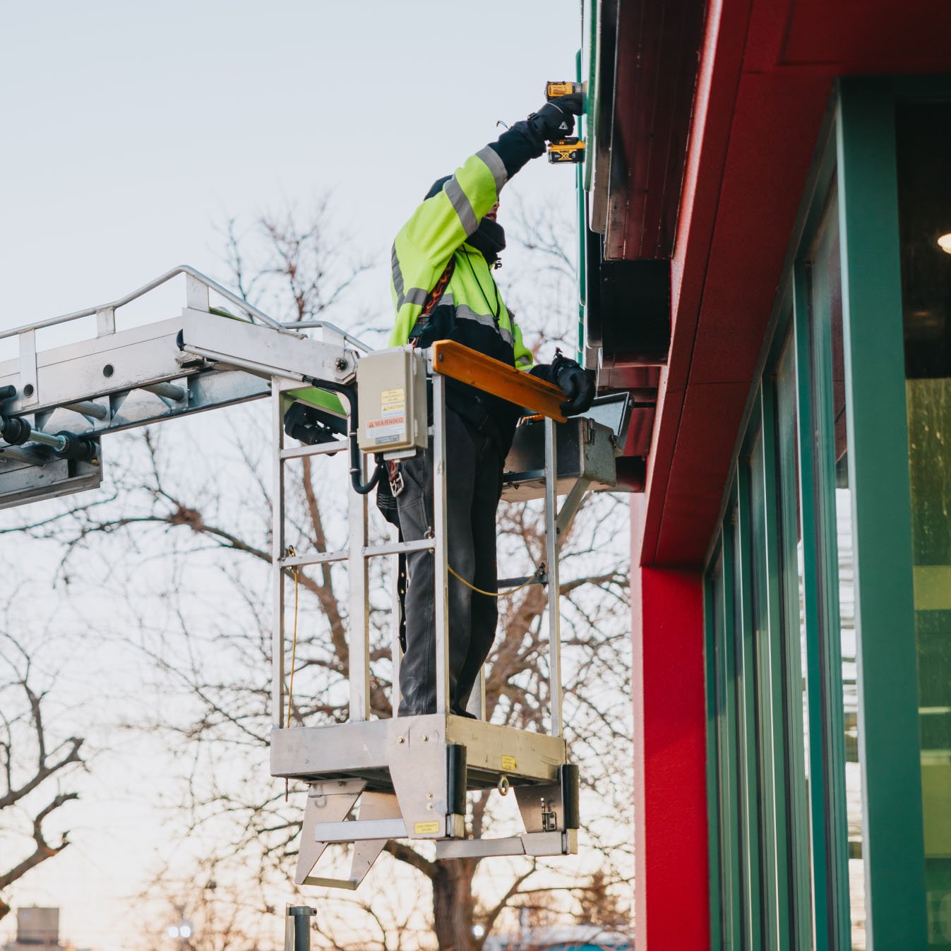 Rick Signs technician in bucket truck reaching up to a commercial illuminated sign in Chicago