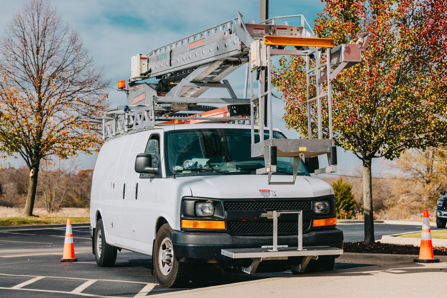 Rick Signs Van Ladder bucket truck and service van on a Chicago job site during autumn