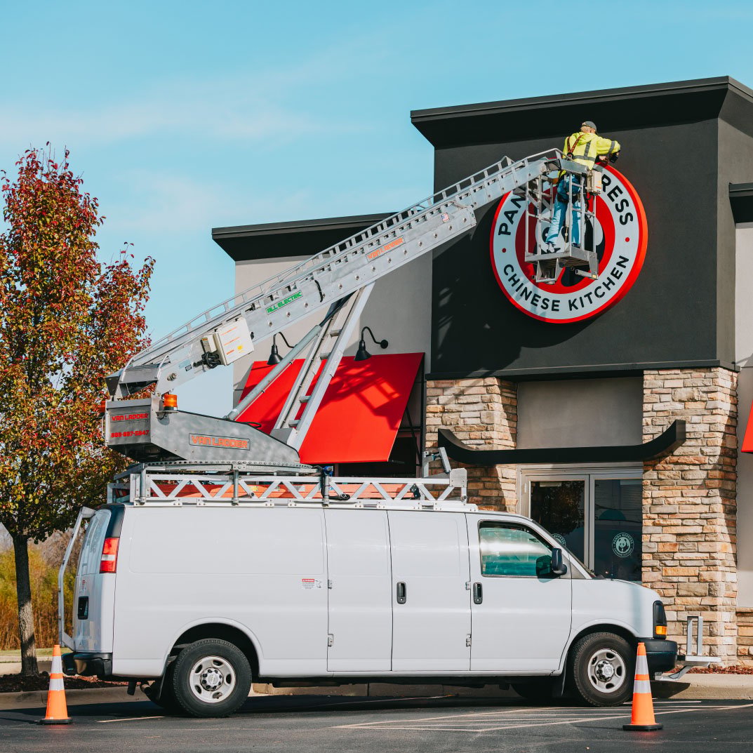 Rick Signs service van and bucket truck arriving at a Panda Express location for a storefront sign repair in Chicago