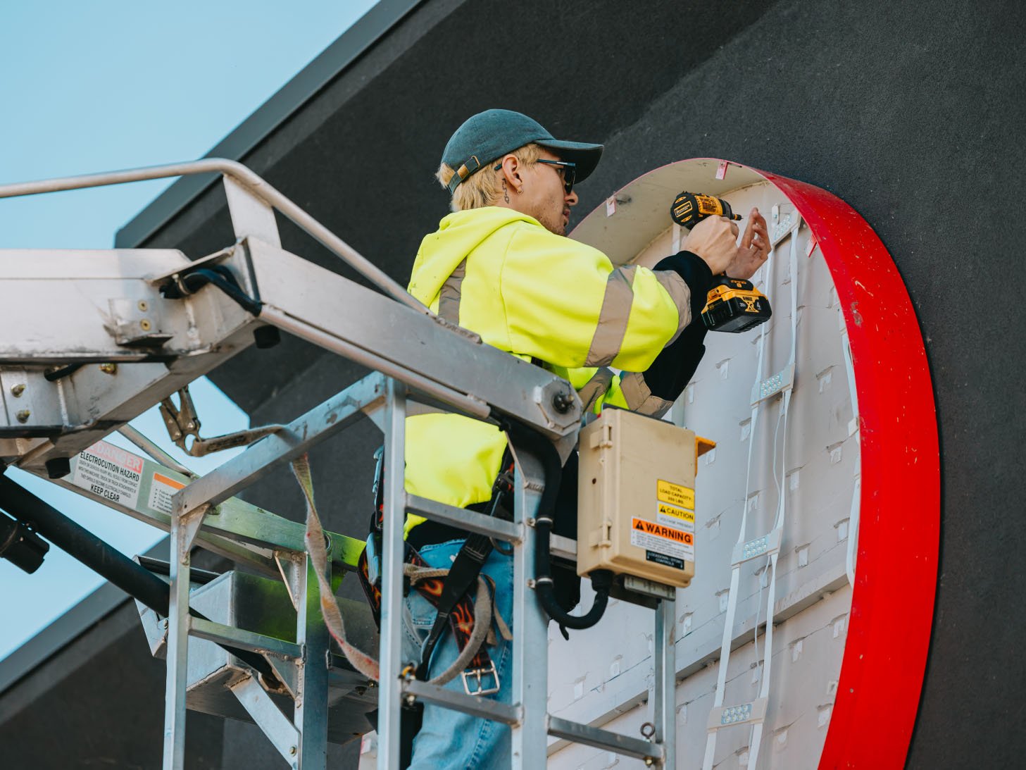 Tymothy Mough on the bucket truck working on a red channel letter sign installing LED modules — Rick Signs Chicago