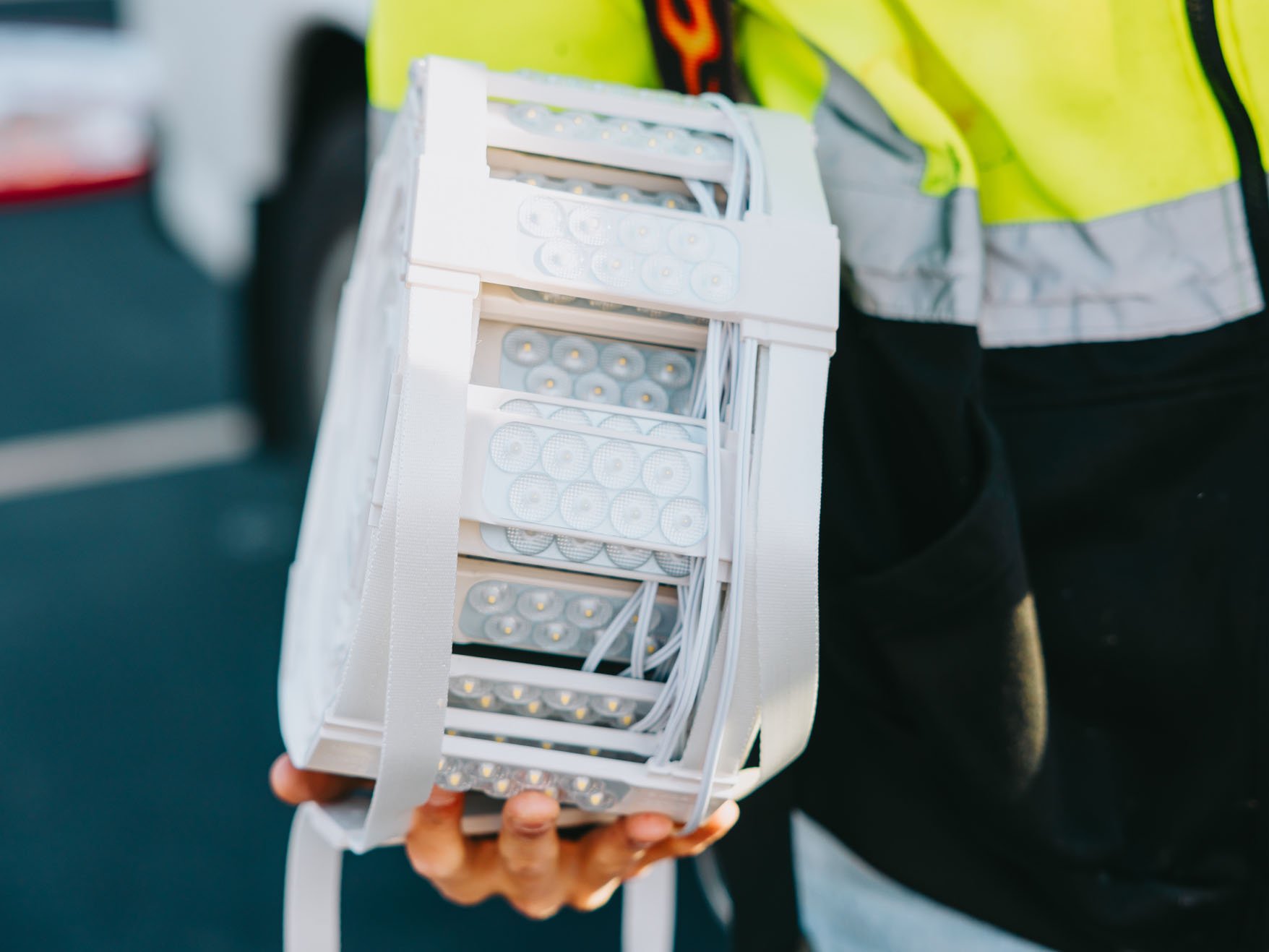 Rick Signs technician in safety gear holding an LED driver power supply during a Chicago sign repair