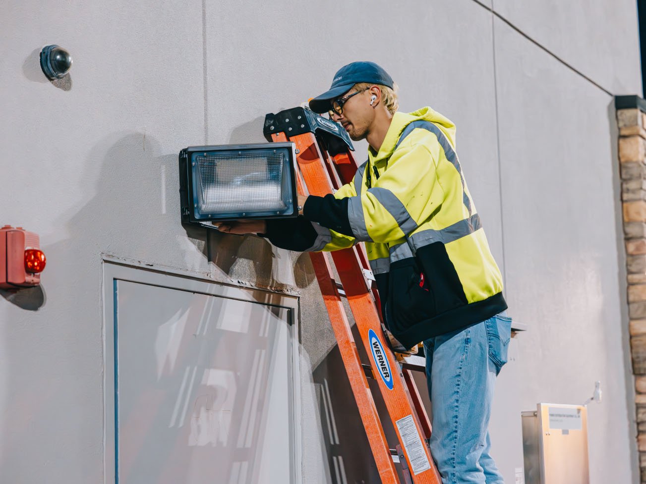 Tymothy Mough drilling sign mounts during a Chicago commercial sign install for Rick Signs