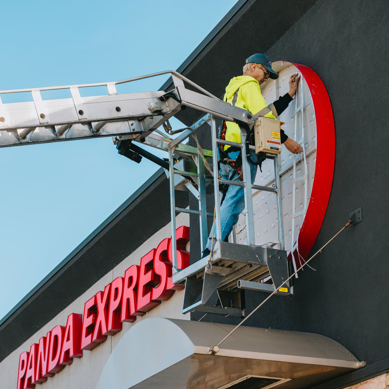 Rick Signs technician in bucket truck repairing the EXPRESS channel letters on a Panda Express storefront in Chicago