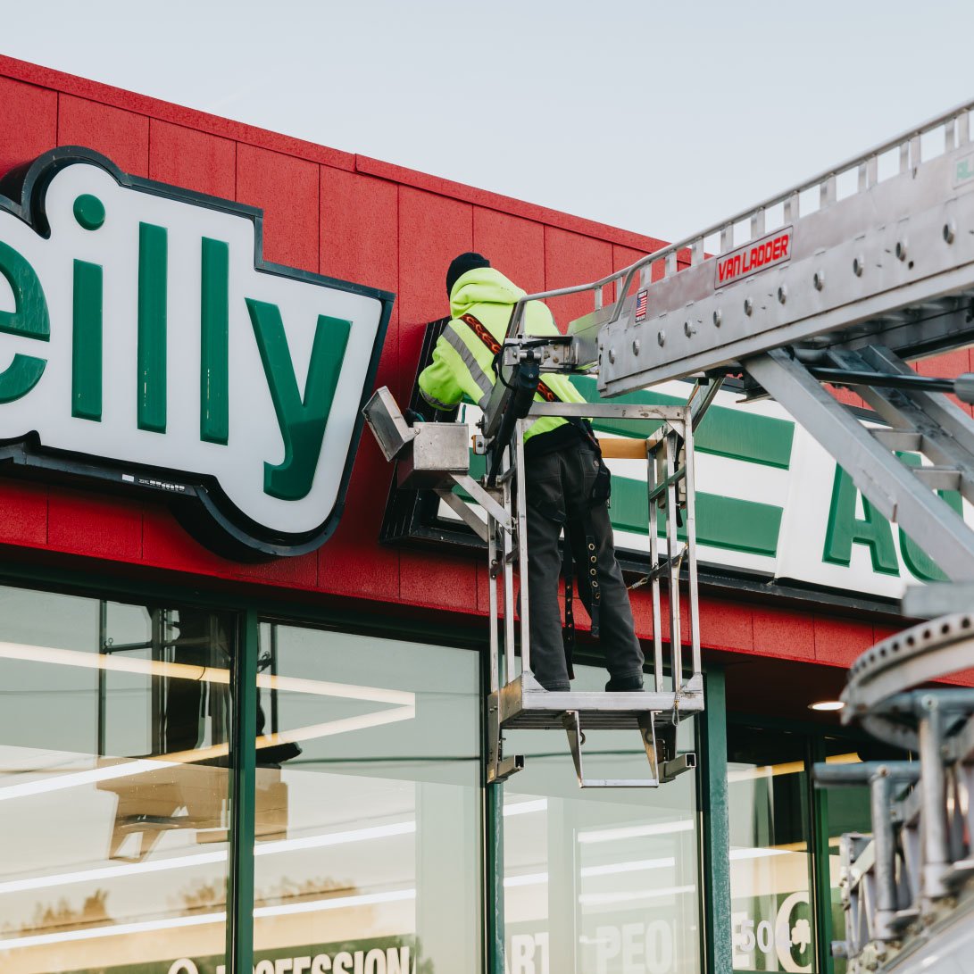 Rick Signs bucket truck and scaffolding setup at an O’Reilly Auto Parts storefront sign installation in Chicago
