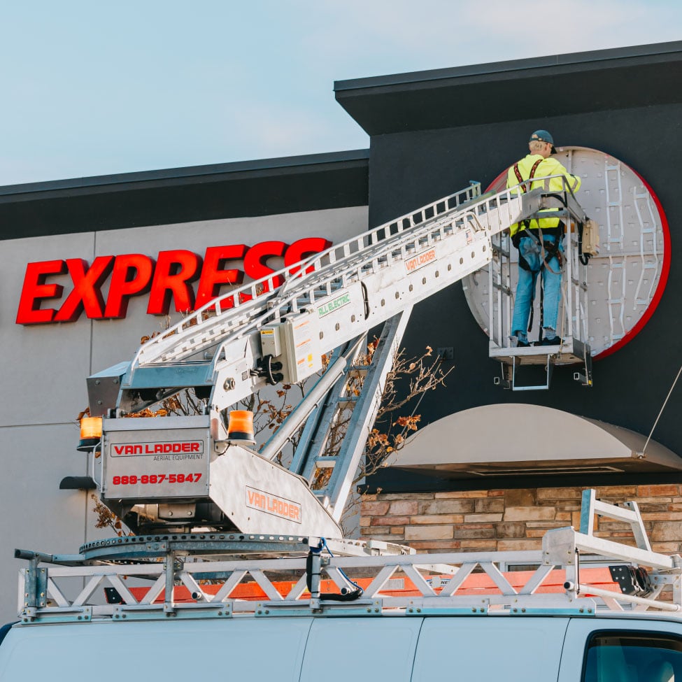 Wider view of Rick Signs bucket truck working on the red Panda Express channel letter storefront sign in Chicago