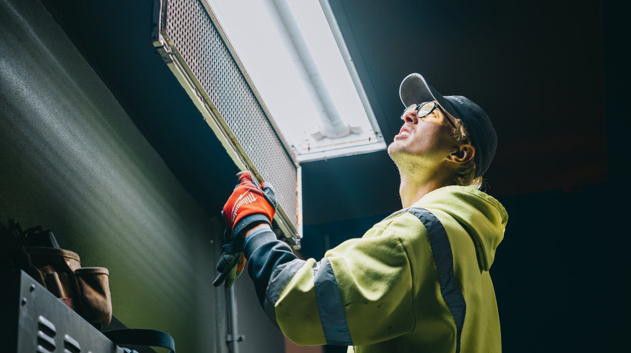 Rick Signs technician reaching up to swap a fluorescent tube during a commercial interior lighting repair in Chicago
