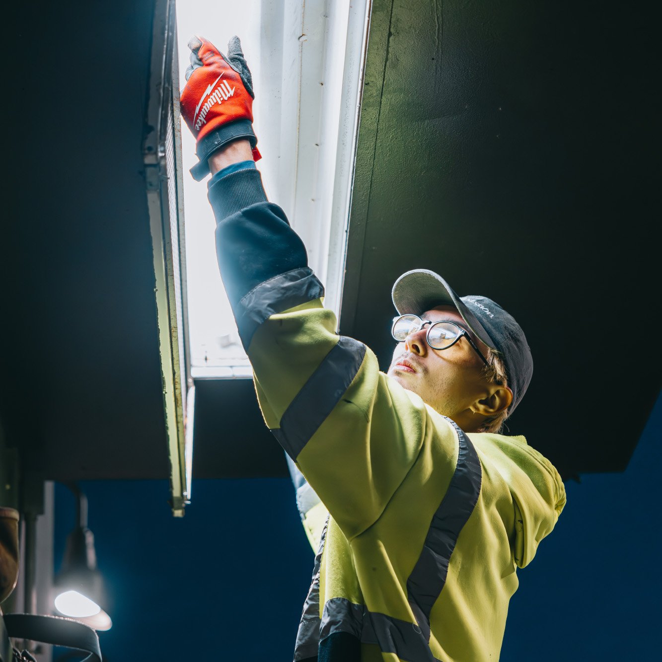 Tymothy Mough replacing a fluorescent tube fixture during an interior commercial lighting repair — Rick Signs Chicago