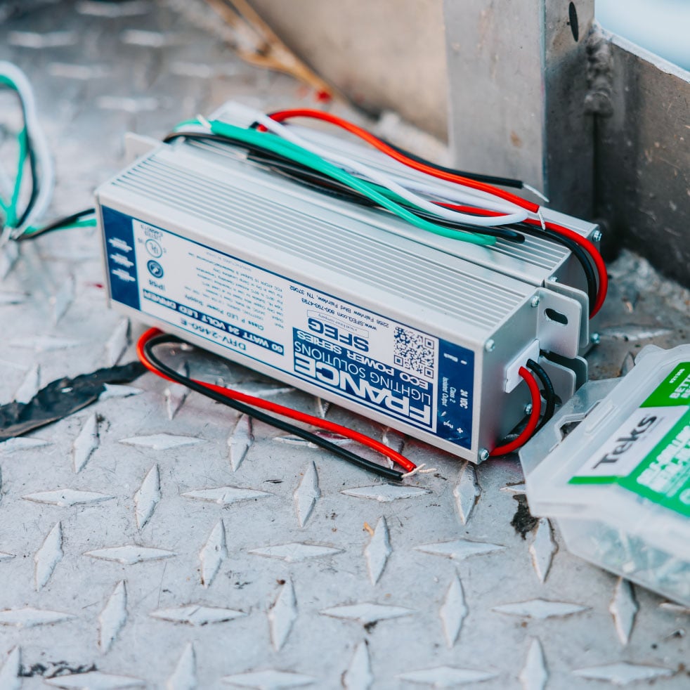Close-up of an LED driver and power supply held by Rick Signs technician — sign electrical repair parts