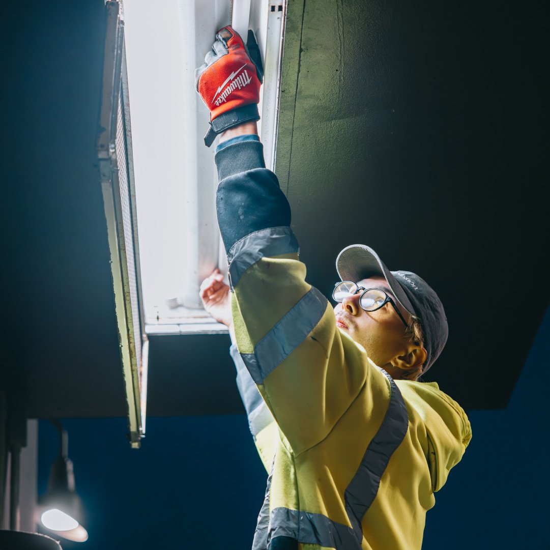 Rick Signs technician carrying a long fluorescent tube during a commercial lighting maintenance call in Chicago