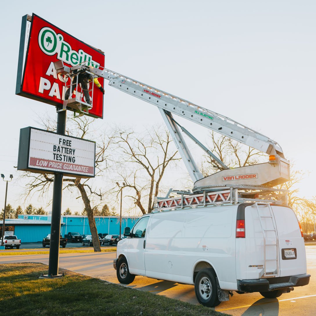 Rick Signs Van Ladder bucket truck and service van positioned at a tall commercial pole sign in Chicago