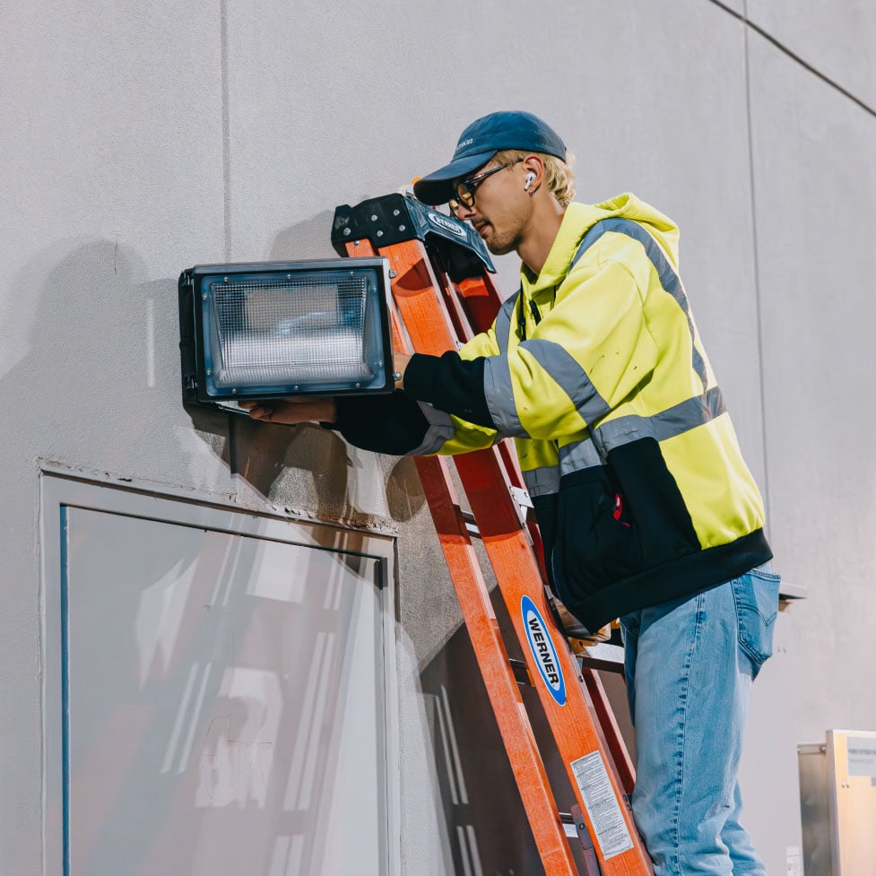 Rick Signs technician operating ground equipment outside a commercial building during a sign service call in Chicago