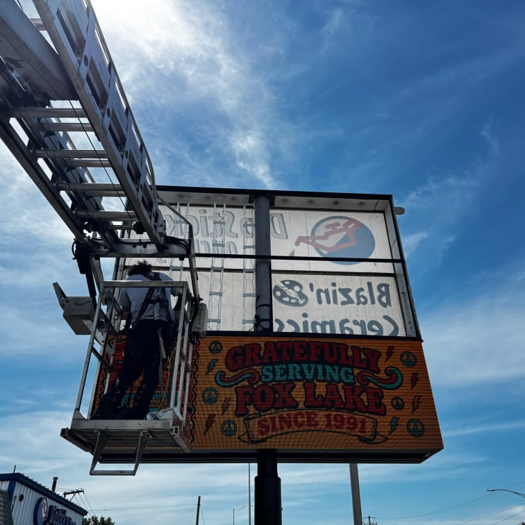 Rick Signs bucket truck servicing a retail storefront illuminated sign in Chicago