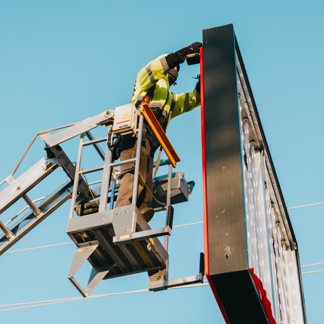 Rick Signs bucket truck reaching the panels of a commercial cabinet sign in Chicago