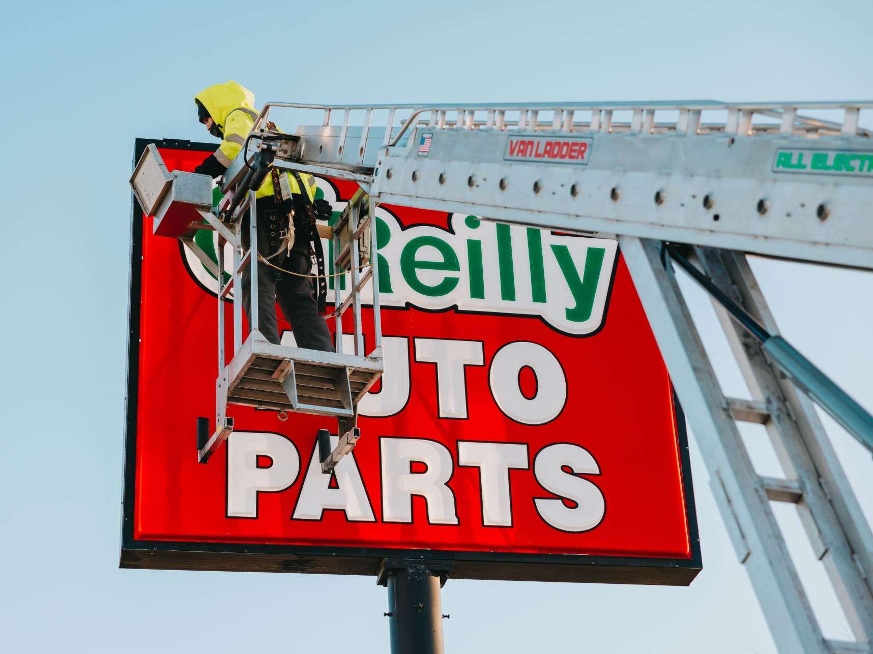 Close-up of the O’Reilly Auto Parts illuminated cabinet pole sign with Rick Signs bucket truck servicing it in Chicago